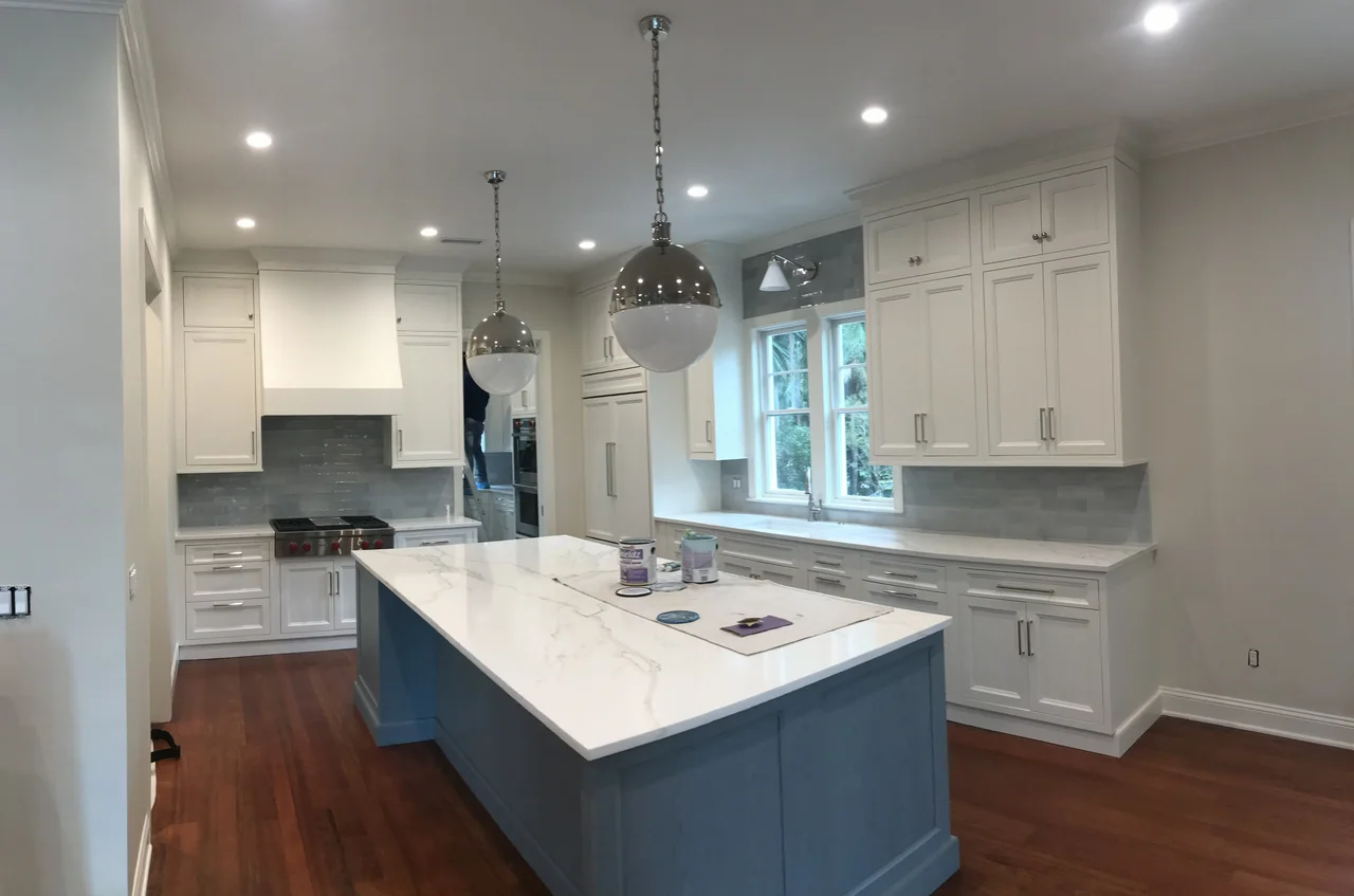 White kitchen with a central island and glass pendant lights