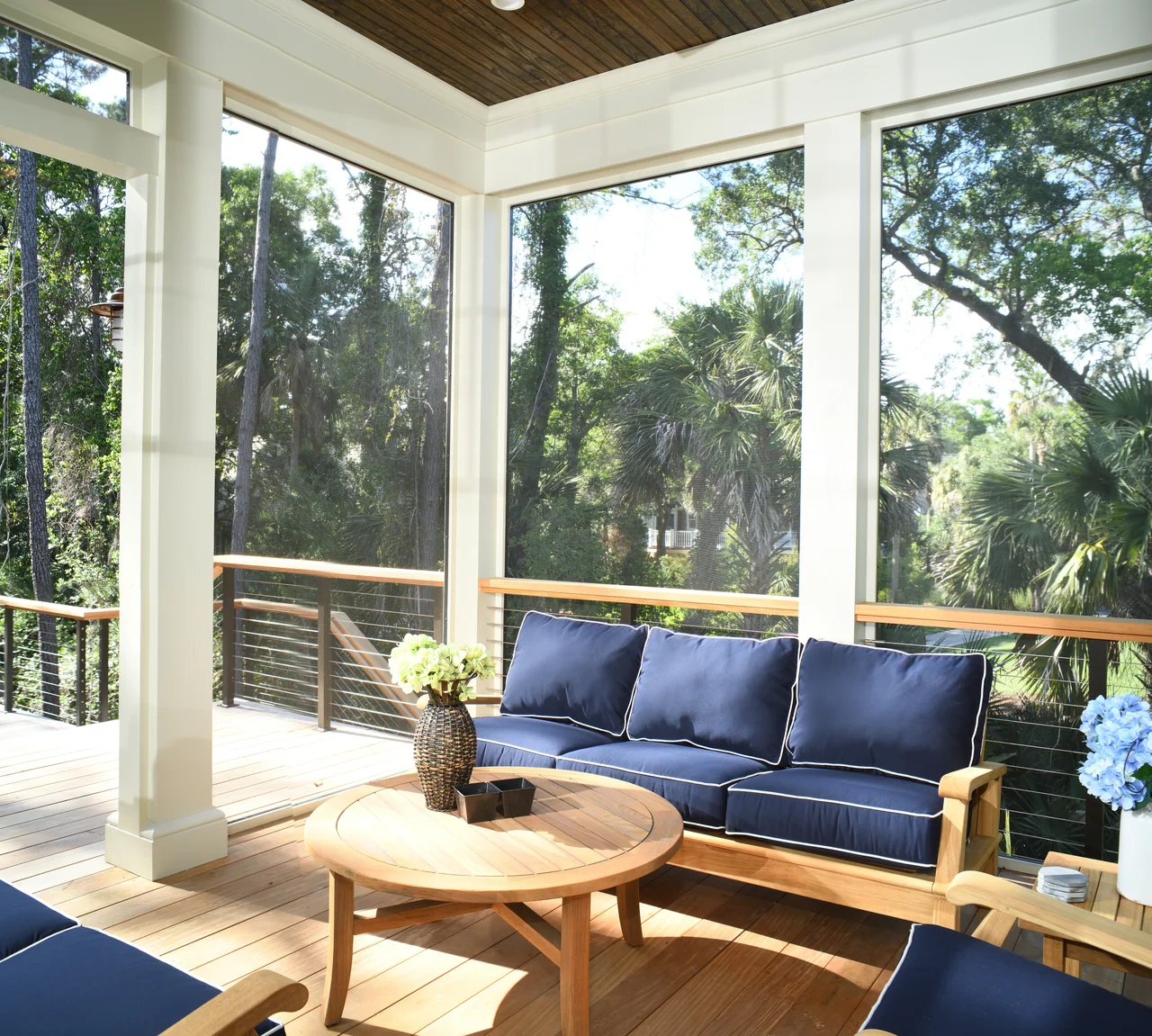 Screened porch with blue cushions and a wood coffee table