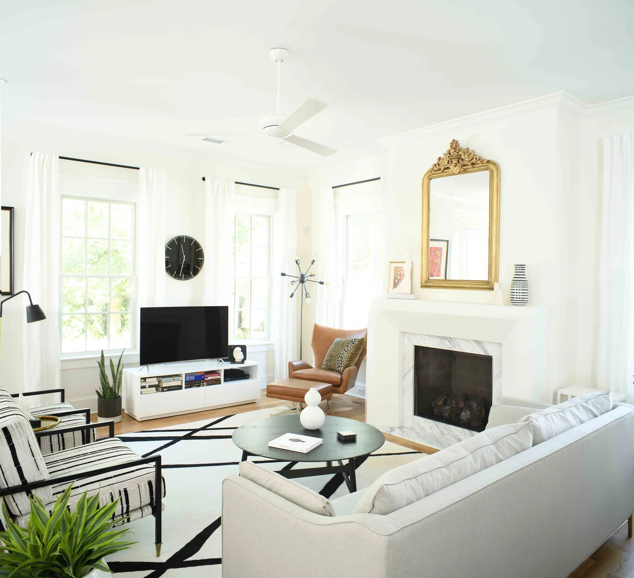 Living room with a white fireplace, pale upholstery and colorful art